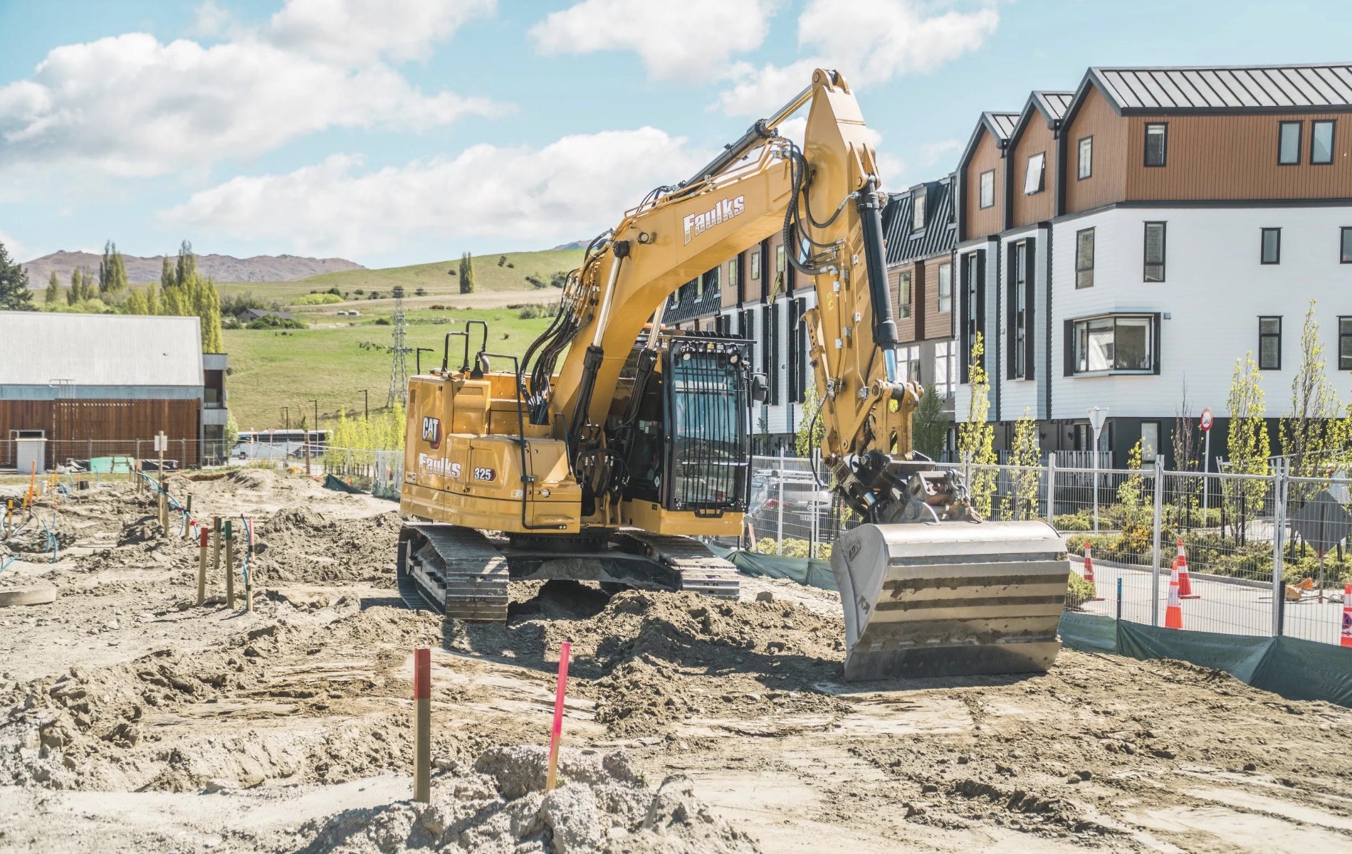 An excavator working beside homes at a residential construction site